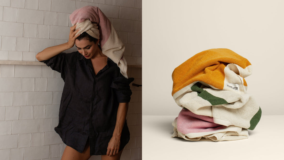 A woman wearing a luxurious towel on her head and a pile of crumpled towels.